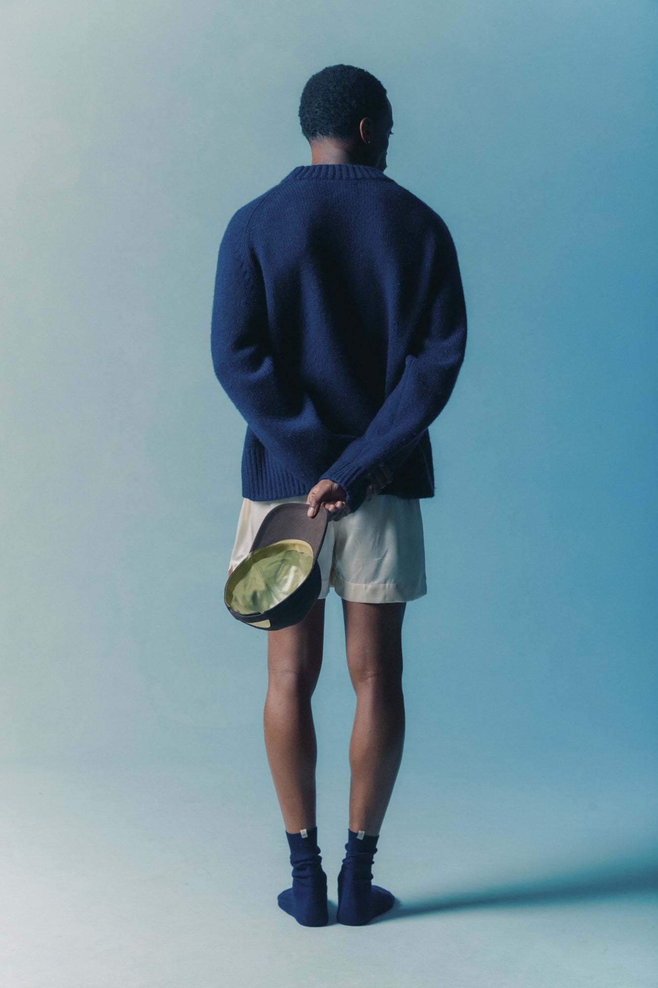 Myron holds the silk-lined baseball cap in brown, with mint silk interior lining visible, with la boxer classica silk in cream and the merino sock in navy, shot by vanessa granda