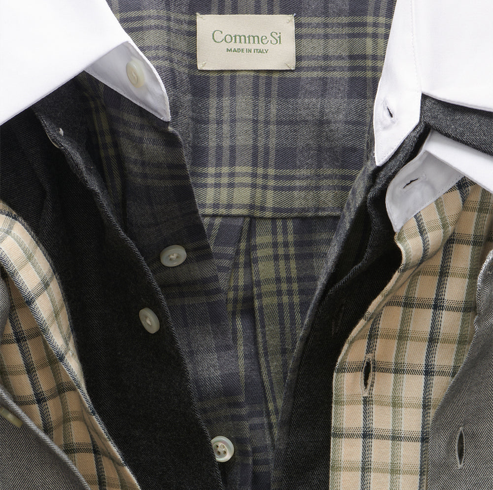Close-up of layered gray and butter plaid shirts with white collars and Comme Si labels.