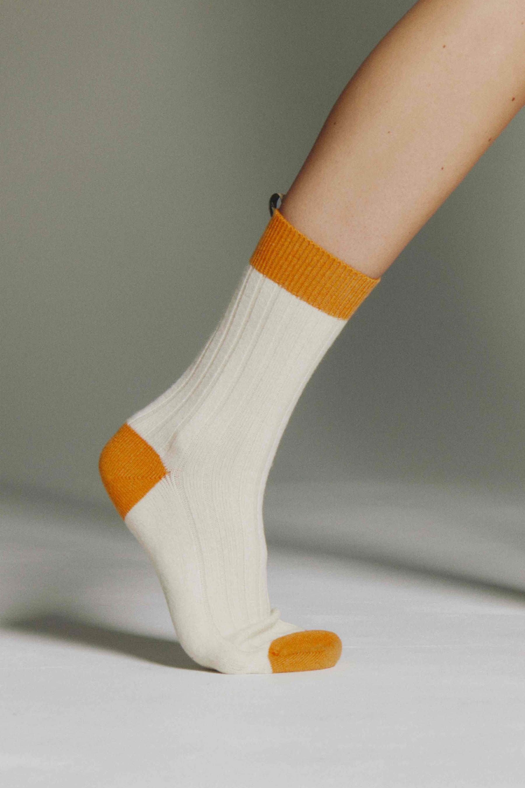 The Danielle Sock, Color Block in Cream / Tangerine on a flexed foot